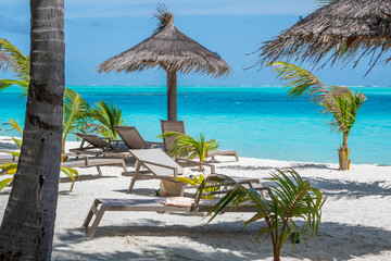 Beautiful tropical beach with white sand and several sun loungers on background of turquoise ocean...