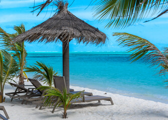 Beautiful tropical beach with white sand and two sun loungers on background of turquoise ocean and blue sky with clouds. Luxury resort in Maldives 2022