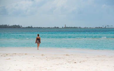 Fototapeta na wymiar Woman walking along the beach with turquoise water, in tropical paradise, in Maldives Island 2022