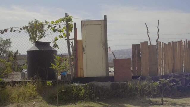 Puerta de madera en casa rural de d&iacute;a soleado en la Ciudad de M&eacute;xico. Cerca, tinaco. Plano general