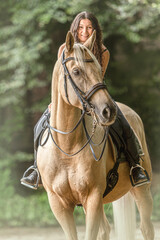 Equestrian scene: A female rider on a palomino kinsky warmblood horse during warm up for dressage...