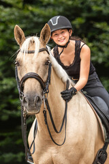 Equestrian scene: A female rider on a palomino kinsky warmblood horse during warm up for dressage...