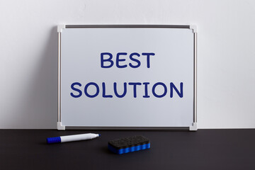 Whiteboard on black table with text BEST SOLUTION. Business concept.