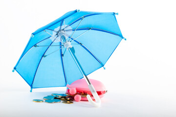 Pink wallet with coins under a blue umbrella on a white background. Insurance concept.
