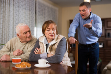 Fototapeta na wymiar Adult son argues with his elderly parents at home. High quality photo
