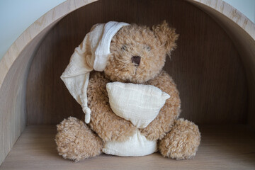 Plush toy sleeping teddy bear sits on a shelf