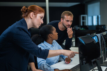 Colleagues discuss work. African young woman, caucasian and red-haired caucasian communicate in the office. 