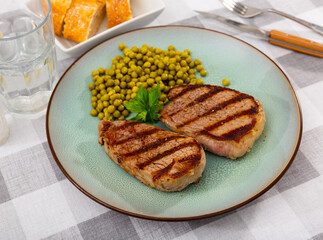 Beef steak with green peas served on plate. Grilled beef meat with peas.