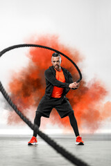 Battle rope functional training. Man on cross exercises. Fit athletic man doing fitness outdoors.