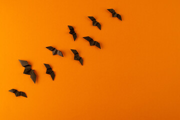 Black origami bats on orange background. Orange and black paper halloween background