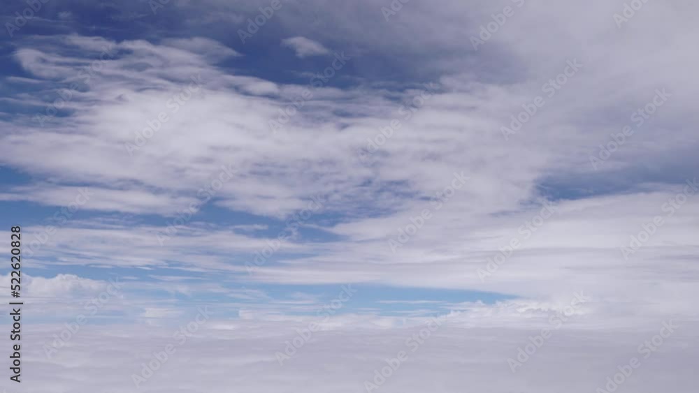 Wall mural aerial view from airplane window as it flies between layers of white clouds with blue sky beyond.
