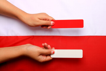 Obraz premium Hand holding red and white paper as a symbol of the Indonesian flag. Indonesia's Independence Day August 17th.