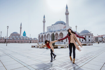 mother playing around with her daughter in the square while visiting mosque in konya turkiye