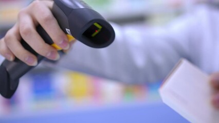 Close-up scanning bar code of pills with scanner in pharmacy indoors in slow motion. Unrecognizable pharmacist selling medication in drugstore. Service and pharmaceutical industry concept