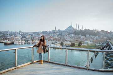 asian woman leaning on a bridge looking at panoramic view of beautiful city of instanbul and bosphorus in turkey