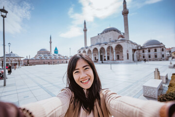 beautiful asian woman taking selfie portrait in front of the mosque in konya turkey