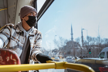 Portrait of young asian man with mask looking through window of a bus