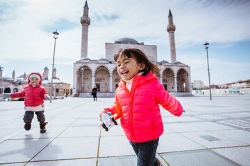 happy kid running around the square in city centre of konya turkey with mosque in the background