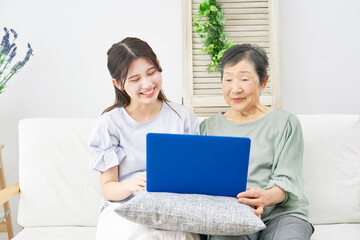 自宅でノートパソコンを使う孫と祖母