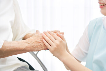Fototapeta na wymiar 高齢者女性の手を握る介護士の手元