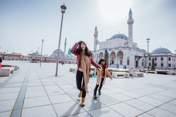 mother playing around with her daughter in the square while visiting mosque in konya turkiye