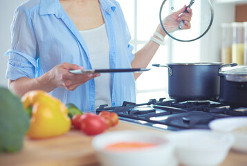 Young woman standing by the stove in the kitchen