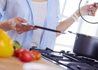 Young woman standing by the stove in the kitchen