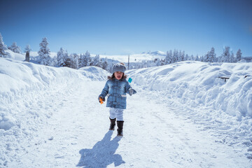 Fototapeta na wymiar cute little kid walking alone in the middle of snowy mountain
