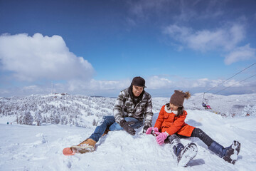 Fototapeta na wymiar happy father and daughter playing with snow in the mountain peak