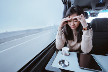 frustrated asian young woman while sitting inside a car or a van with big window