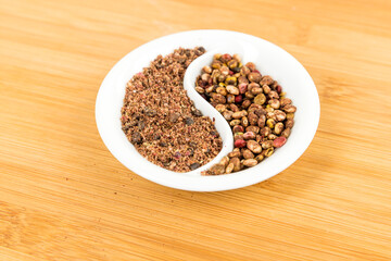 Whole dried sumac berries and ground powder in a yin yang bowl over wood board
