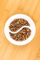 Whole dried sumac berries in a yin yang bowl over wood board top down
