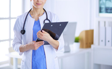 Young smiling female doctor with stethoscope holding a folder at doctor's office