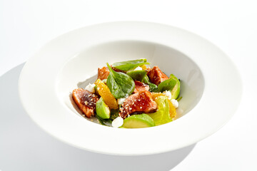 Healthy lunch - green salad with tuna, avocado and orange. Tuna salad for diet. Clean eating in restaurant menu. Grilled Fish with spinach, avocado, citrus isolated on white background. Keto diet.