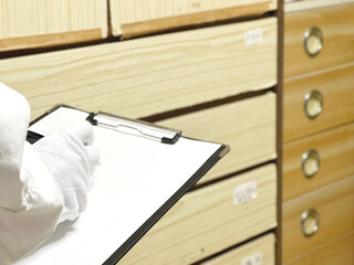 古いタンスを査定するクリップボードを持った白手袋の手元