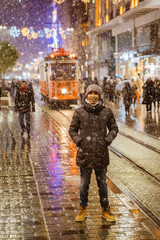 man standing in the middle of the road enjoying snow fall in winter holiday