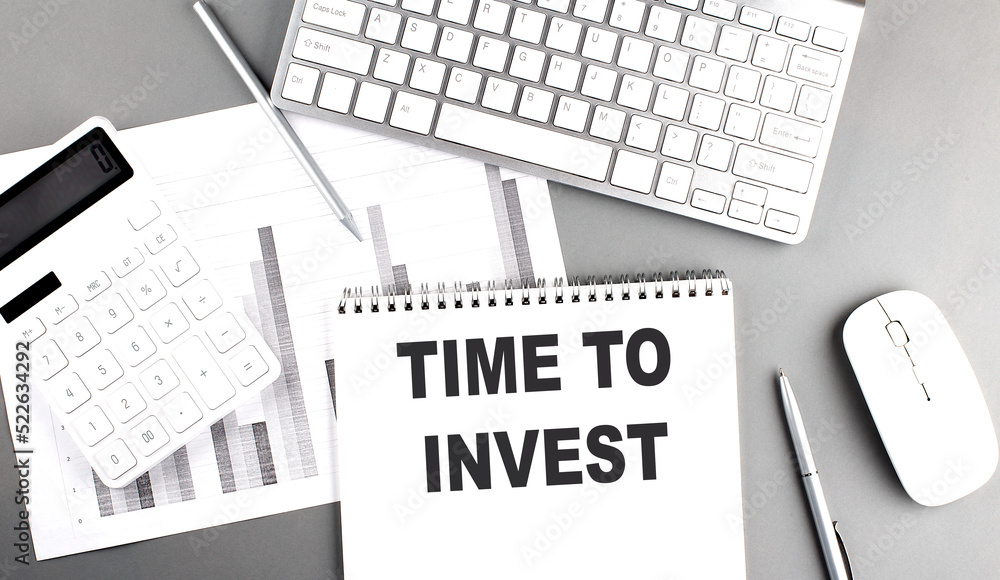 Poster time to invest text written on notebook on grey background with chart and keyboard , business concep