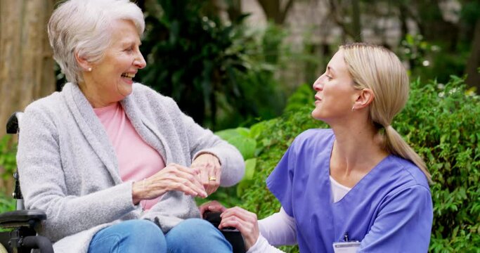 Loving, Caring Nurse Assisting A Disabled Senior Lady In A Wheelchair Outside In A Garden At Retirement Home. Smiling Retired Woman Enjoying A Relaxing Day Together With A Geriatric Healthcare Worker