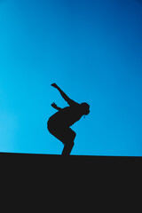 Silhouette of a man doing warm-ups in the park. Man practicing exercise with the sky in the background.