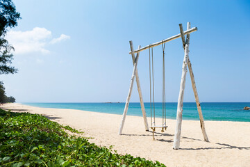 Relaxing by the sea, wooden swing on white sandy beach on tropical island in south of Thailand, summer outdoor day light