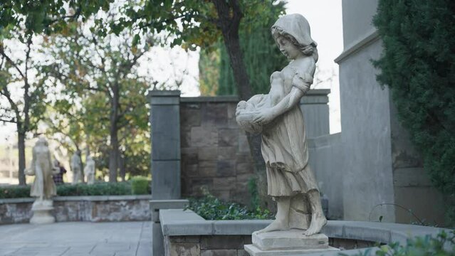 Statue of a girl holding some dogs in a basket in the park