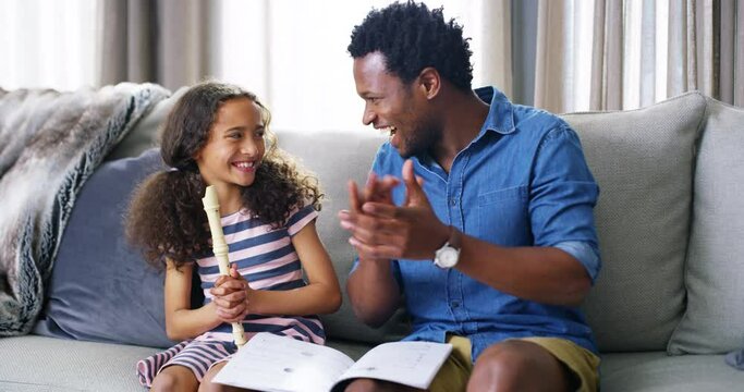 Father clapping for daughter playing a flute in home living room while cheering and supporting her. Happy, smiling and proud parent bonding with child and celebrating her learning musical instrument