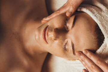 Caucasian freckled woman having a facial massage beauty treatment. Natural woman beauty, skincare....