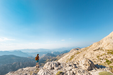 young girl with a backpack walks along a mountain path