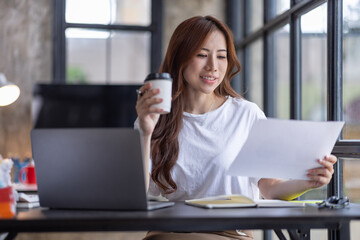 Business Asian woman freelancer is working her job on computer laptop from home office Doing accounting analysis report real estate investment data, Financial and tax systems concept.