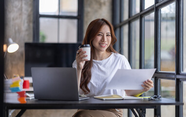 Fototapeta premium Business Asian woman freelancer is working her job on computer laptop from home office Doing accounting analysis report real estate investment data, Financial and tax systems concept.