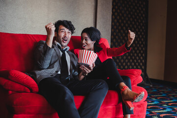 Caucasian white man and African woman enjoying a movie in the cinema.