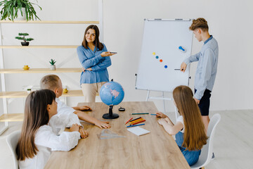 A teacher and students of different ages at a geography lesson. The student answers by standing...