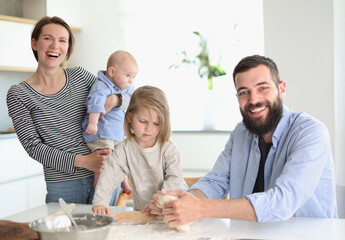 Young parents playing with children in the kitchen