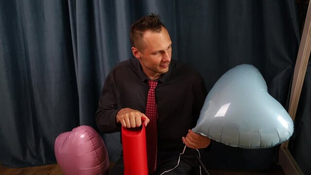 A man inflating a balloon. man decorater inflates colorful balloons with compressor for feast, holiday